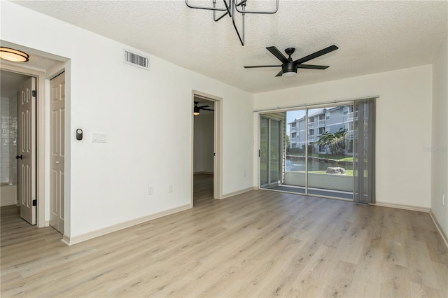 interior space with ceiling fan with notable chandelier, light wood-type flooring, and a textured ceiling