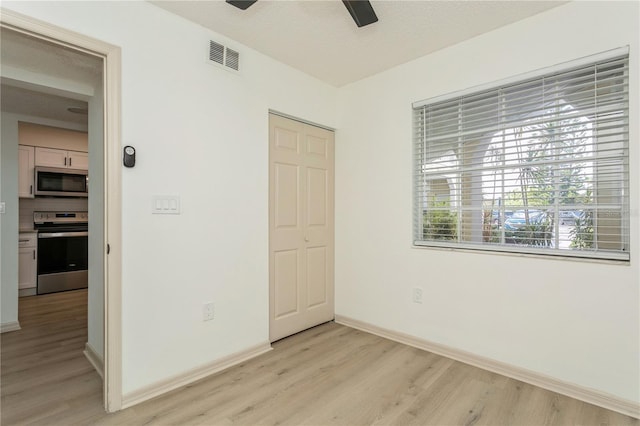 unfurnished bedroom with ceiling fan, multiple windows, light hardwood / wood-style flooring, and a closet