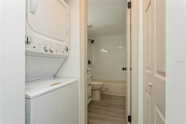 clothes washing area featuring light wood-type flooring and stacked washing maching and dryer