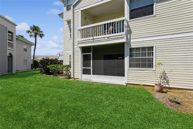 rear view of property featuring a balcony and a yard