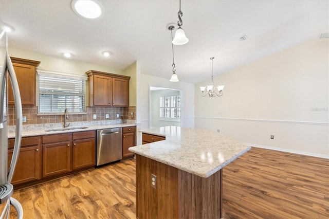 kitchen with a kitchen island, light hardwood / wood-style flooring, sink, pendant lighting, and appliances with stainless steel finishes