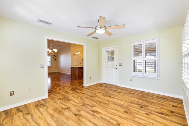 spare room with wood-type flooring and ceiling fan with notable chandelier