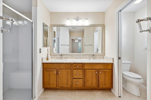 bathroom with toilet, ceiling fan, vanity, and a shower with door