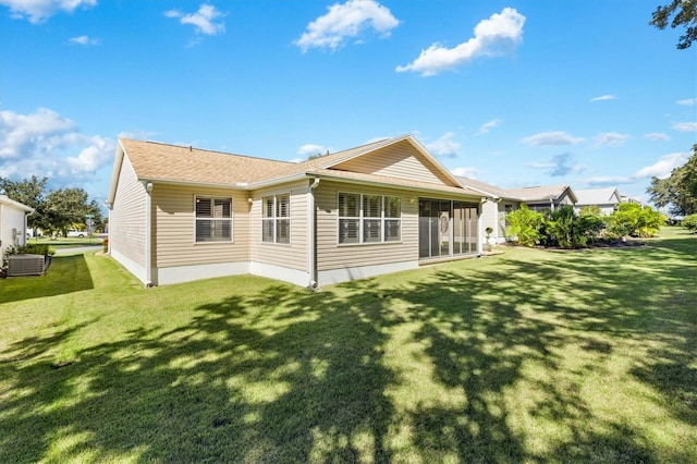 rear view of house with central air condition unit and a lawn