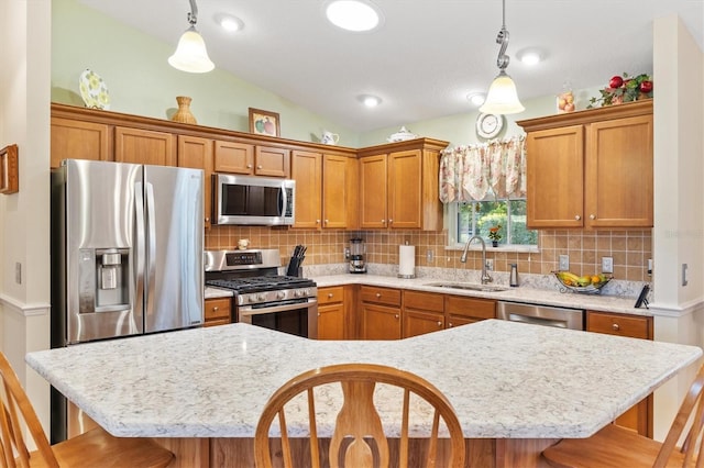 kitchen with a breakfast bar, vaulted ceiling, sink, pendant lighting, and stainless steel appliances