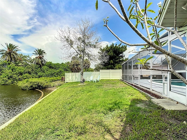 view of yard with a lanai and a water view