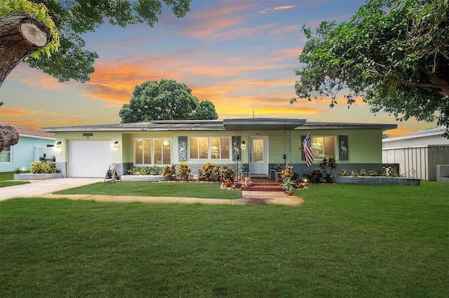 ranch-style home with a garage, concrete driveway, and a lawn