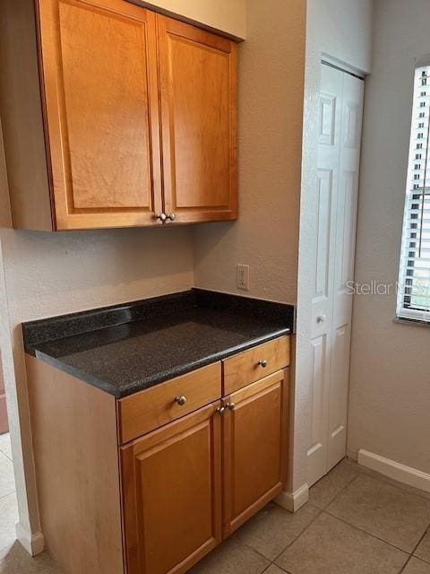 kitchen with light tile patterned flooring and dark stone countertops