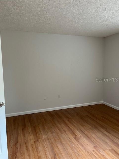 unfurnished room with wood-type flooring and a textured ceiling