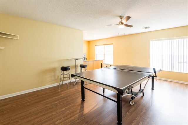 rec room with dark wood-type flooring, a textured ceiling, and ceiling fan