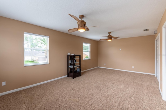 carpeted spare room featuring ceiling fan and a textured ceiling