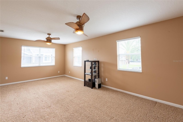 carpeted empty room with ceiling fan and a healthy amount of sunlight