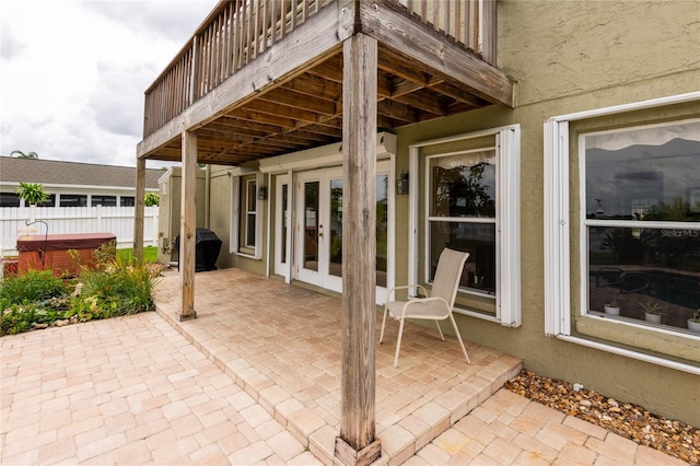 view of patio / terrace featuring a hot tub, french doors, and a balcony