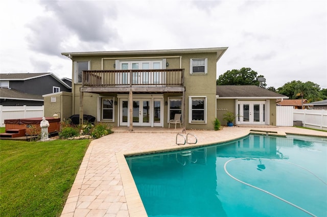 rear view of house featuring a pool with hot tub, a patio, a lawn, and french doors