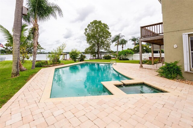 view of swimming pool featuring a deck, a patio, a lawn, and an in ground hot tub