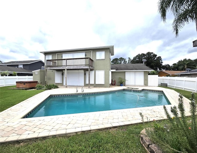 rear view of property featuring a patio, a lawn, a balcony, and a swimming pool with hot tub