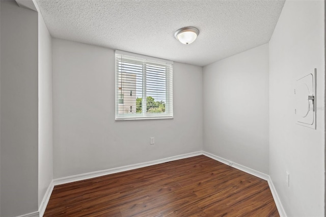 unfurnished room featuring a textured ceiling and dark hardwood / wood-style flooring