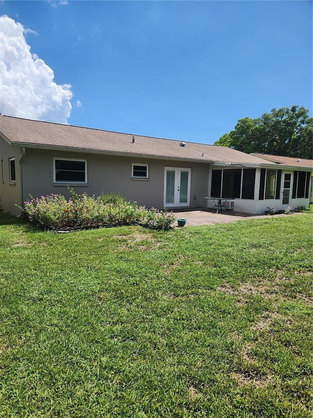 back of property featuring a patio, a yard, a sunroom, and french doors