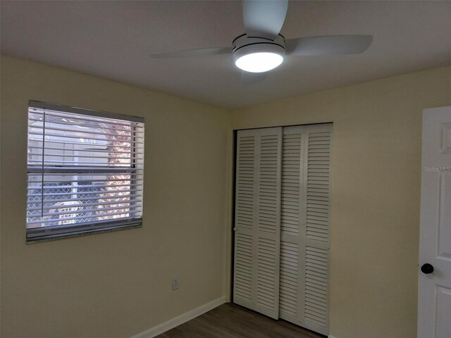 unfurnished bedroom with dark hardwood / wood-style flooring, a closet, and ceiling fan