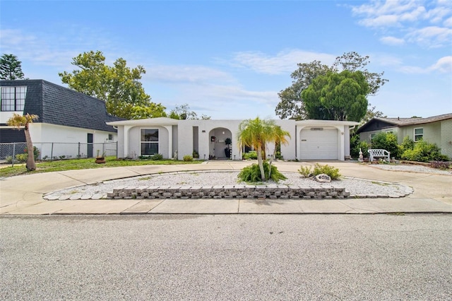 view of front facade with a garage, driveway, mansard roof, and fence