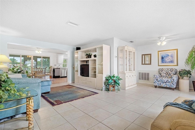 living room with a textured ceiling, ceiling fan, light tile patterned flooring, and visible vents