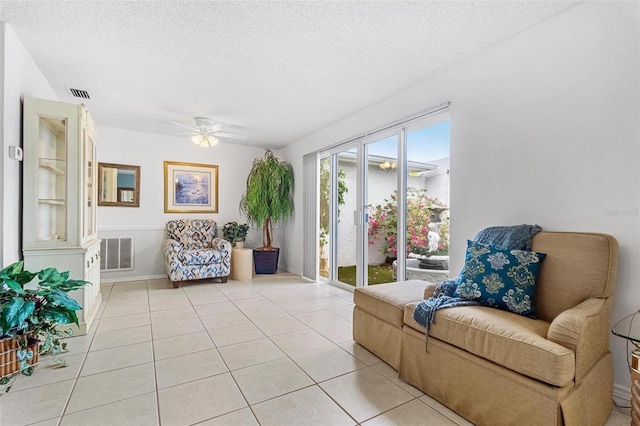 sitting room with light tile patterned floors, ceiling fan, visible vents, and a textured ceiling