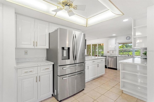 kitchen featuring appliances with stainless steel finishes, light countertops, white cabinetry, open shelves, and a sink