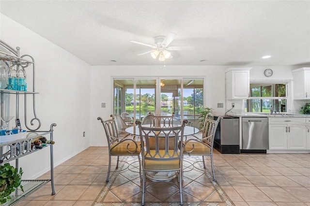 dining space featuring light tile patterned floors, a ceiling fan, baseboards, and a textured ceiling