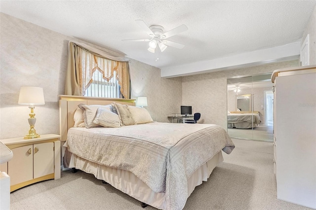 bedroom with light carpet, ceiling fan, a textured ceiling, and wallpapered walls