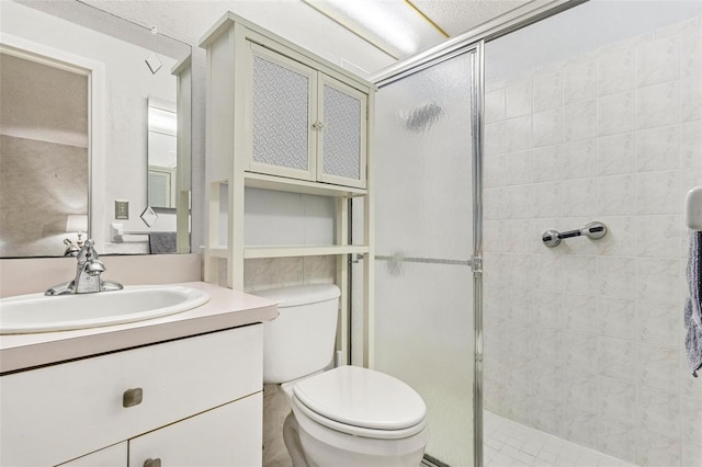 bathroom featuring toilet, a stall shower, and vanity