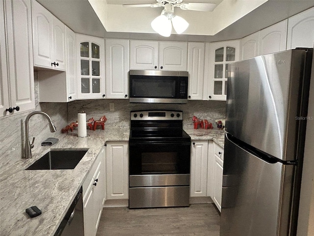 kitchen featuring ceiling fan, decorative backsplash, a raised ceiling, and stainless steel appliances