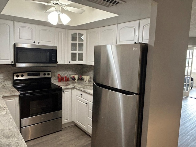 kitchen featuring backsplash, ceiling fan, light wood-type flooring, and stainless steel appliances