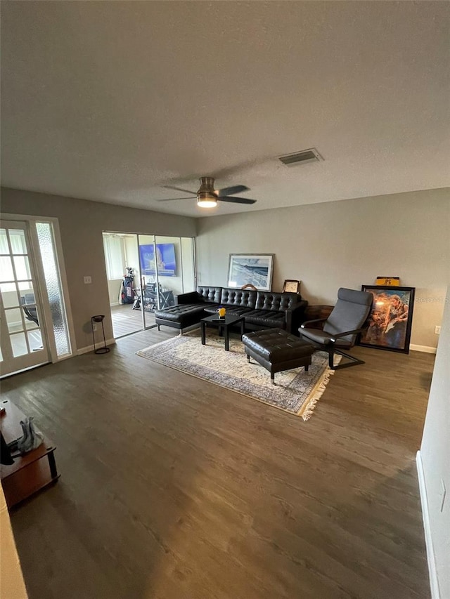 living room with a textured ceiling, wood-type flooring, and ceiling fan