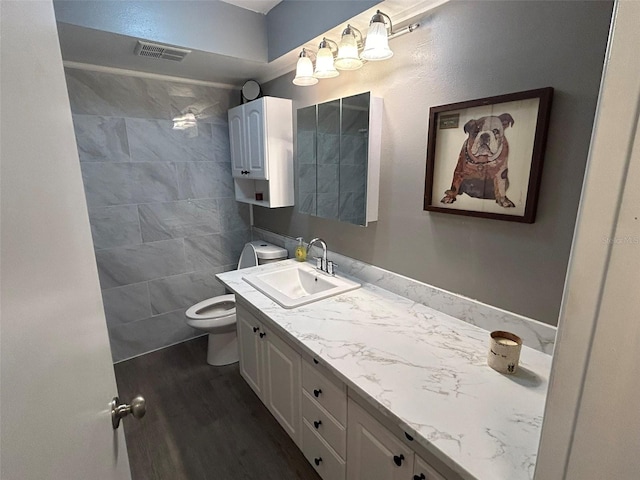 bathroom with hardwood / wood-style floors, tile walls, toilet, and vanity