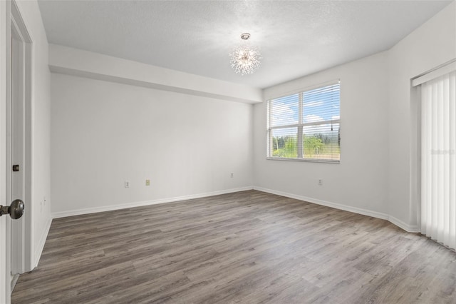 empty room featuring a textured ceiling, baseboards, and wood finished floors