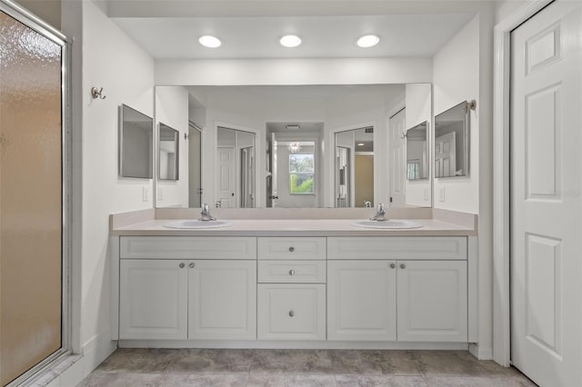 full bath featuring double vanity, a shower stall, a sink, and recessed lighting