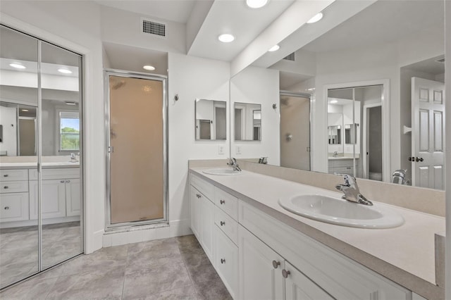 full bathroom with visible vents, a sink, a shower stall, and double vanity