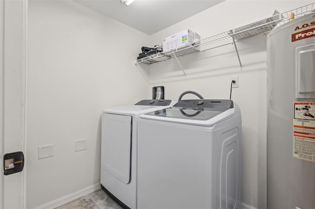 clothes washing area featuring laundry area, water heater, baseboards, and washer and dryer