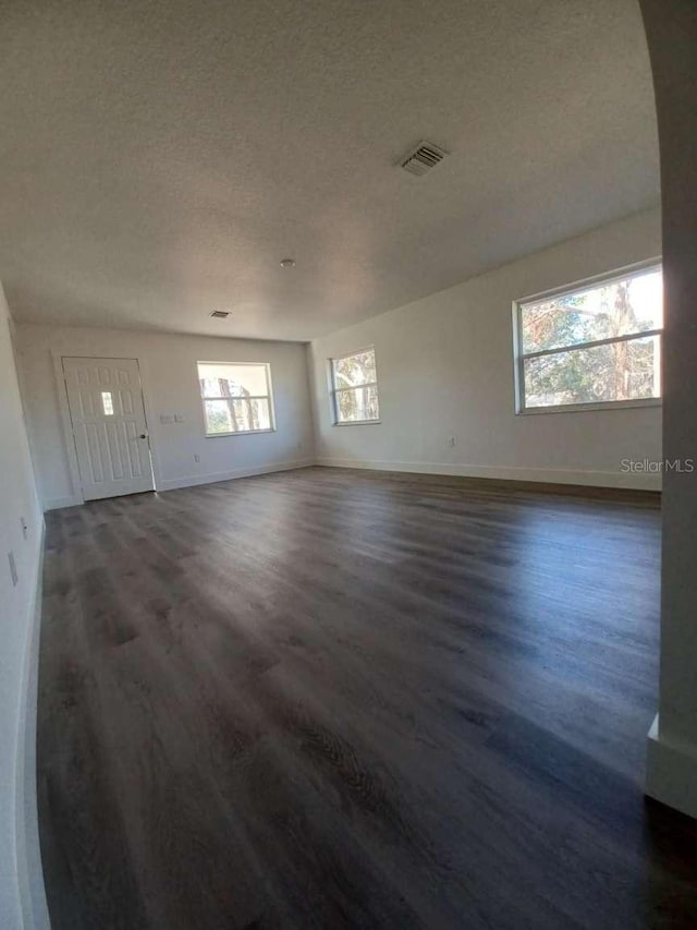 unfurnished living room featuring a textured ceiling and dark wood-type flooring