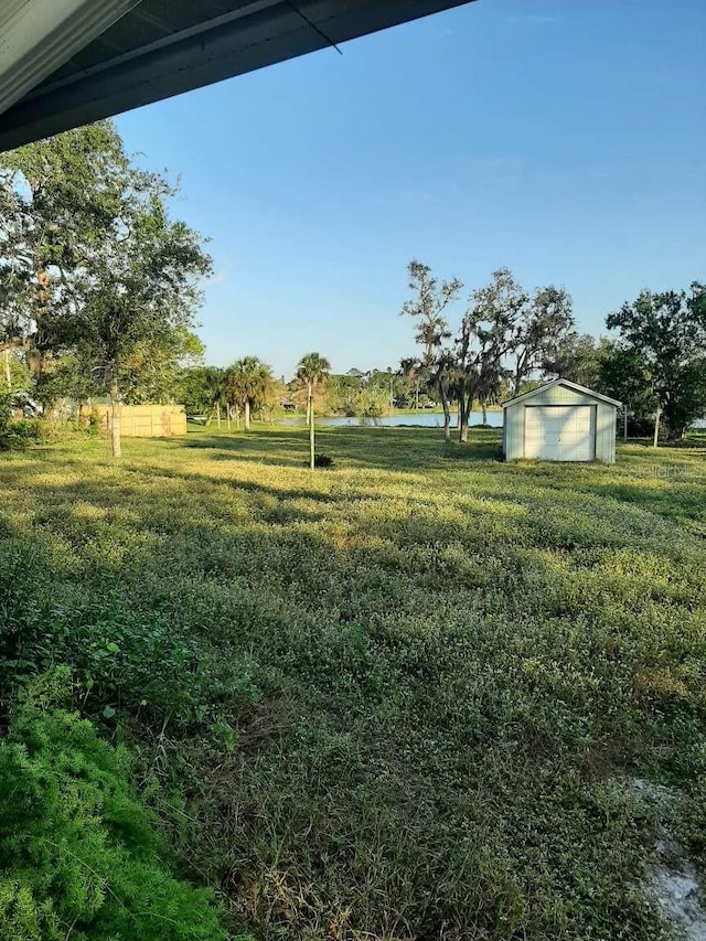 view of yard featuring a water view, an outdoor structure, and a garage