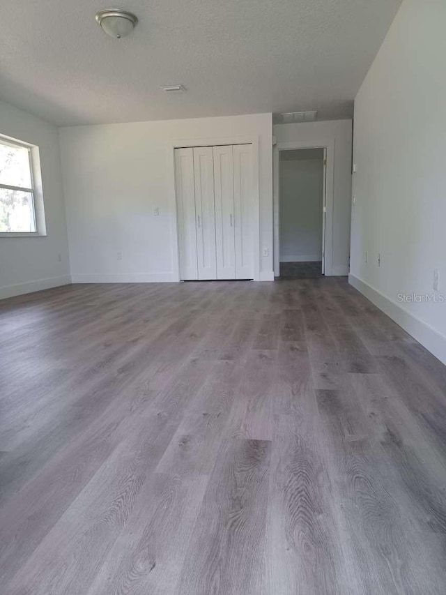 unfurnished bedroom with a textured ceiling, light wood-type flooring, and a closet