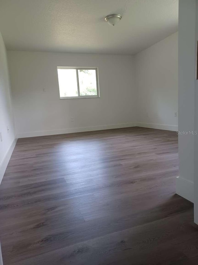 empty room with dark hardwood / wood-style flooring