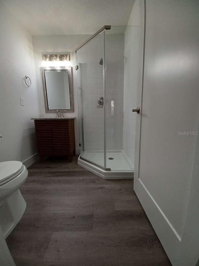 bathroom with walk in shower, vanity, toilet, and hardwood / wood-style flooring