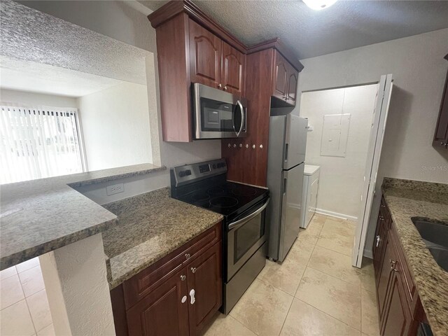 kitchen featuring kitchen peninsula, appliances with stainless steel finishes, light tile patterned floors, and a textured ceiling