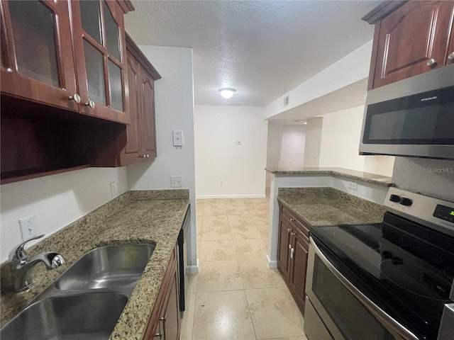 kitchen featuring sink, light tile patterned floors, light stone counters, stainless steel appliances, and a textured ceiling