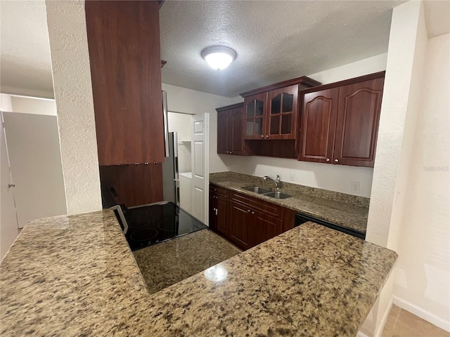 kitchen with sink, stove, light stone counters, kitchen peninsula, and a textured ceiling