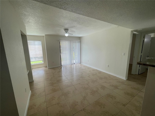 empty room with light tile patterned floors, a textured ceiling, and ceiling fan