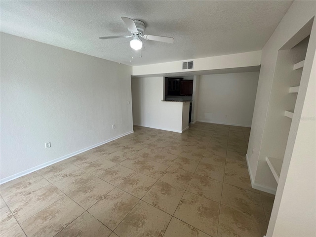 empty room with ceiling fan, a textured ceiling, and light tile patterned floors