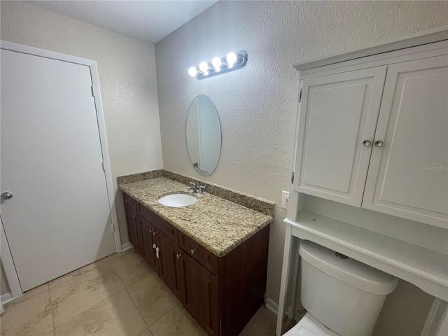 bathroom featuring vanity, a textured ceiling, and toilet