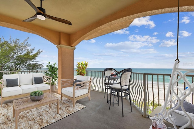 balcony featuring a water view, outdoor lounge area, ceiling fan, and a view of the beach